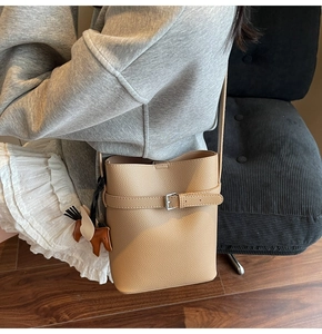 Detail showing litchi grain texture on camel leather bucket bag with horse charm