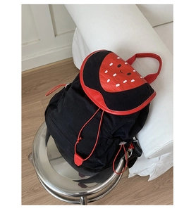Detailed view of a cartoon strawberry themed black backpack with red drawstring and buckle