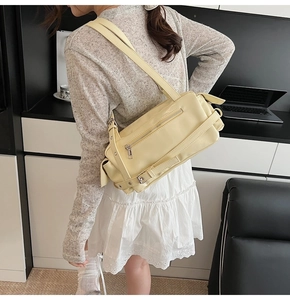 Detail view of cream yellow leather pillow bag showing the side strap and zipper texture