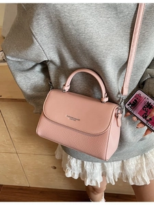Pink lychee texture leather handbag with adjustable strap shown on a fashion model