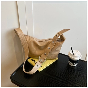 Détail du sac en similicuir camel avec bandoulière large et œillets argentés