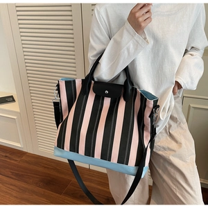 Detail of pink and black striped tote bag with leather handles and blue contrast base
