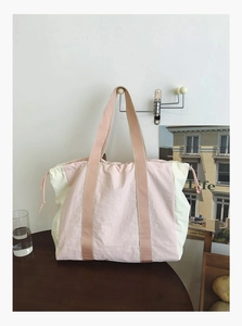 Close-up of pink and beige canvas tote bag showing side drawstrings and wide straps