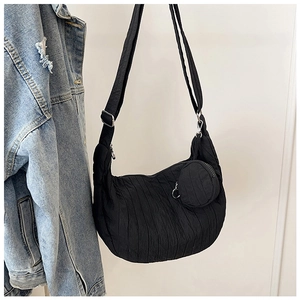 Detail of black croissant shoulder bag featuring a mini round pouch and wide strap