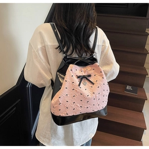 Dettaglio della trama rosa con fiocco e pelle verniciata nera su questo zaino da donna