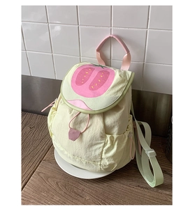 Close-up of yellow nylon backpack featuring strawberry flip cover and green straps