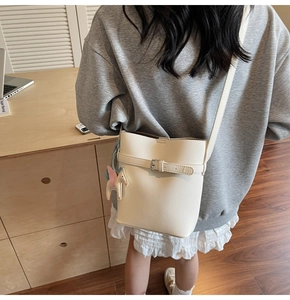 Detailed shot of white lychee pattern bucket bag featuring a cute horse pendant accessory
