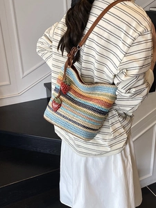 Colorful striped woven bucket bag with strawberry charms and brown leather shoulder strap