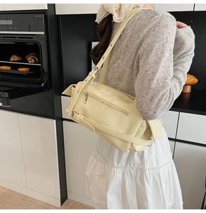 Detail of pale yellow minimalist bowling bag with decorative buckle straps and pockets