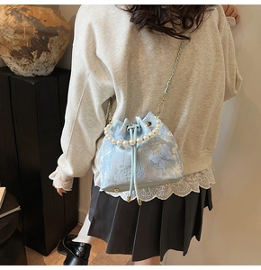 Detail view of light blue lace bucket bag with pearl handle and 3D butterfly accents