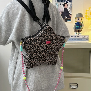 Detail of star-shaped leopard print crossbody bag with colorful woven strap and yellow buckle