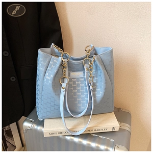 Gros plan du sac cabas bleu clair avec textures gaufrées et poignée dorée