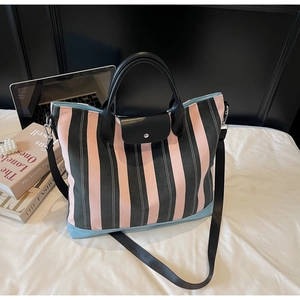 Detail of striped canvas tote bag with snap closure and removable shoulder strap