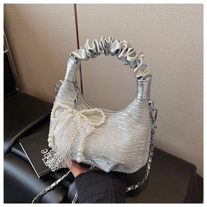 Detail of silver sequin cloud bag featuring a large pearl bow and lace trim