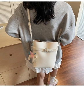Detail of white lychee leather bucket bag with adjustable strap and horse charm detail