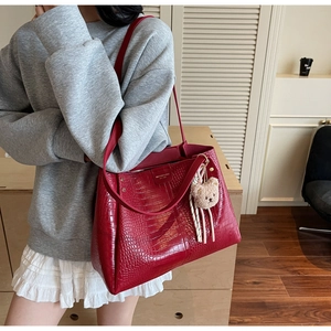 Model wearing a large red crocodile pattern tote bag with a cute bear keychain