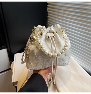 Detail of white bucket bag with floral lace, pearl handle and 3D butterfly accents
