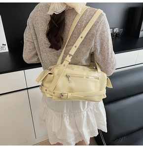 Detail of light beige PU leather pillow bag with adjustable straps on a shoulder model