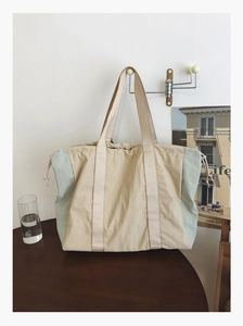 Close-up of beige and mint green large capacity tote bag with adjustable drawstring straps