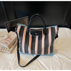 Detail view of pink striped tote bag with black leather flap and reinforced light blue base