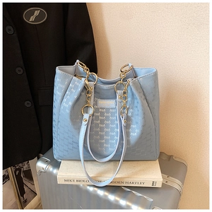 Détail du sac cabas bleu clair avec textures gaufrées et bandoulière en chaîne métal