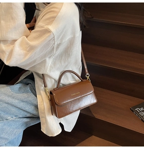 Brown retro leather handbag crossbody bag shown on model sitting on wooden stairs