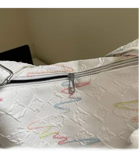 Detail view of white bubble fabric shoulder bag showing smooth metal zipper and wavy embroidery