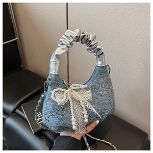 Detail of blue denim bag with crystal grid, pearl fringe, and a large lace bow accent