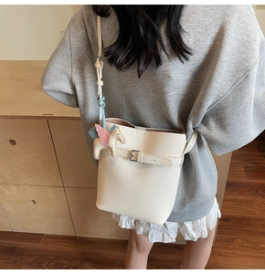 Detail of cream lychee pattern bucket bag with a cute horse charm worn by a model