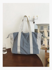 Detail of blue and off-white tote bag with side drawstrings and wide woven shoulder strap