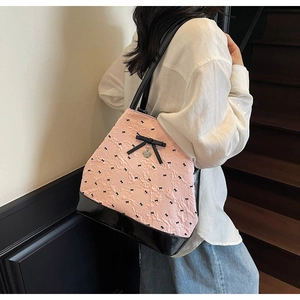 Borsa tote plissettata rosa con fiocchi neri e ciondolo a cuore indossata dal modello