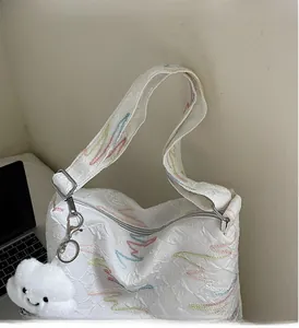 Detail of white canvas tote with colorful wave embroidery and fluffy cloud charm