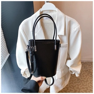 Detail of matte black bucket bag showing the smooth PU texture and silver buckle
