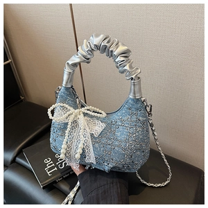 Detail of blue denim bag with silver sequin mesh and large white pearl lace bow
