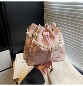 Detailed close-up of pink lace bucket bag featuring floral embroidery and pearl handle