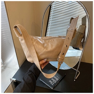 Détails du sac demi-lune beige montrant les coutures et la bandoulière large