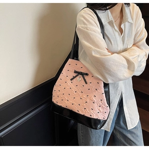 Borsa tote in jacquard rosa con fiocco nero e ciondolo a cuore portata a spalla
