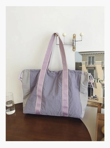 Detail of a large nylon tote bag with purple and gray contrast stitching and drawstring hooks