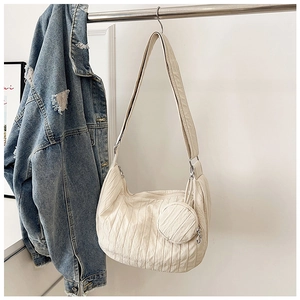 Detail of off-white pleated crossbody bag texture with round mini coin purse attachment
