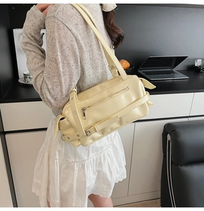Detail of light yellow rectangular pillow bag with zipper pocket and belt buckle design