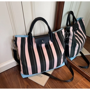 Detail of pink and green striped tote bag with leather flap and detachable shoulder strap