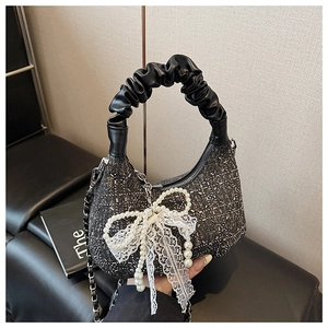Detail of the sparkling rhinestone handbag featuring a pearl bow and ruched leather handle