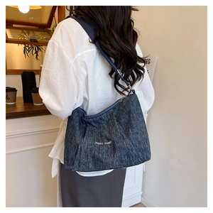 Detail of blue denim tote bag featuring white Happy Sunday embroidery and adjustable strap