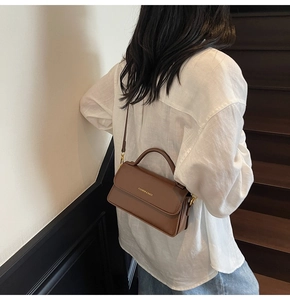 Model wearing a vintage dark brown leather crossbody square bag on a staircase