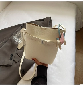 Close-up of beige lychee grain bucket bag featuring a cute elephant leather charm detail