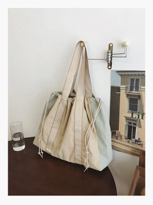 Detail of a large two-tone drawstring tote bag hanging with natural lighting