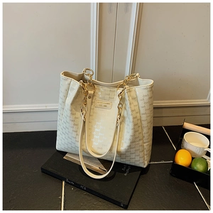 Détail du sac cabas crème à monogramme avec bandoulière chaîne et plaque logo dorée