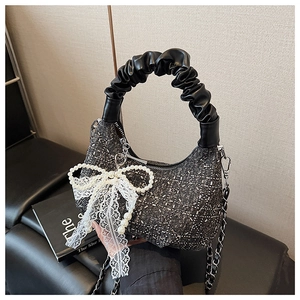 Detail of dark grey hobo bag with glitter fabric, pleated handle and lace bow charm