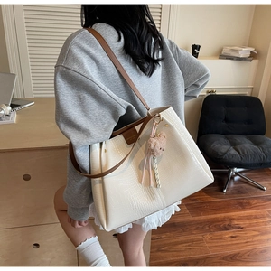 Detail of crocodile embossed cream tote bag with brown leather straps and teddy charm