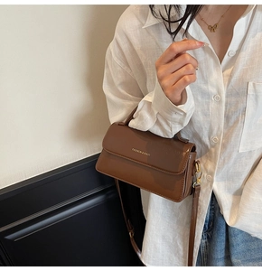 Brown vintage leather shoulder bag with gold hardware shown on a model outfit